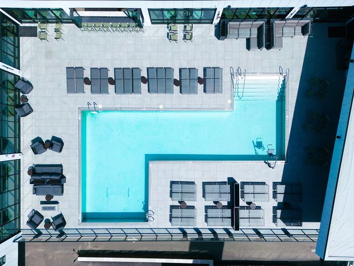 Luxurious rooftop pool area with modern lounge chairs and stylish deck in a high-rise apartment complex.