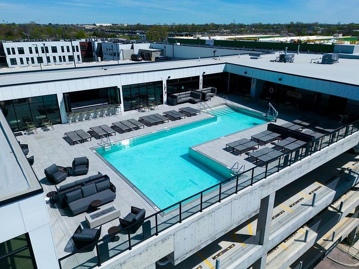Luxurious rooftop pool area with modern lounge chairs and seating, set against a backdrop of urban views.