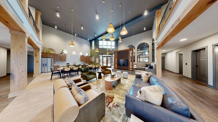 Luxurious open living space with elegant wooden accents, stylish seating, modern lighting fixtures, and a sleek kitchen area.