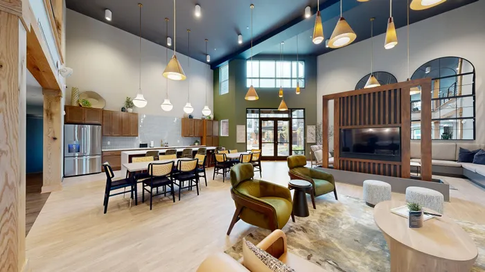 Bright and stylish open-concept living space featuring modern kitchen, dining area, and cozy seating with elegant lighting and a high ceiling.