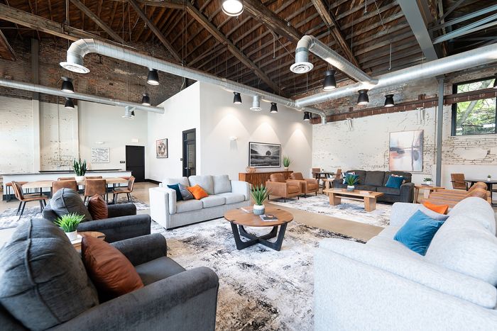 Chic industrial-style living space with exposed brick, high ceilings, modern furnishings, and cozy seating.