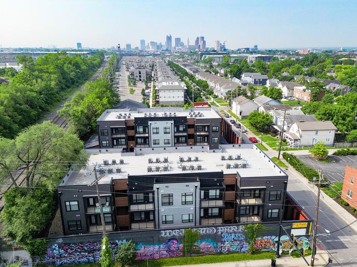 Contemporary apartment complex with vibrant street art, rooftop seating, and lush surroundings.