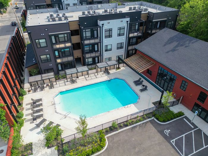 Contemporary apartment complex with vibrant street art, rooftop seating, and lush surroundings.