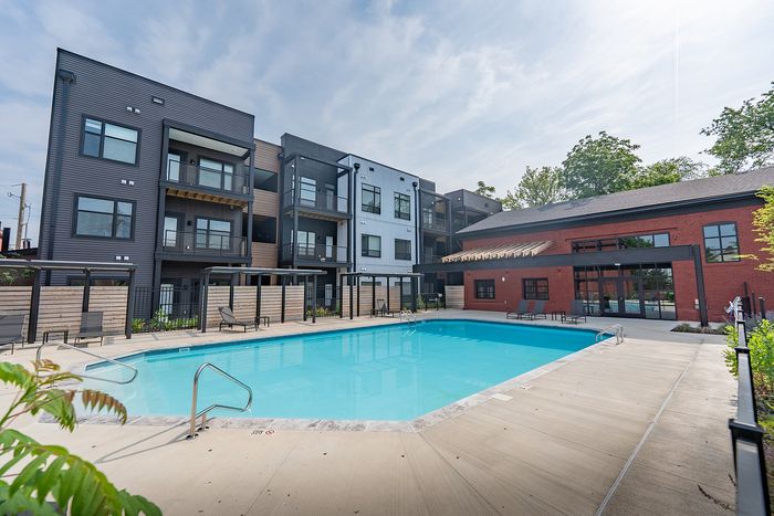 Contemporary apartment complex with vibrant street art, rooftop seating, and lush surroundings.