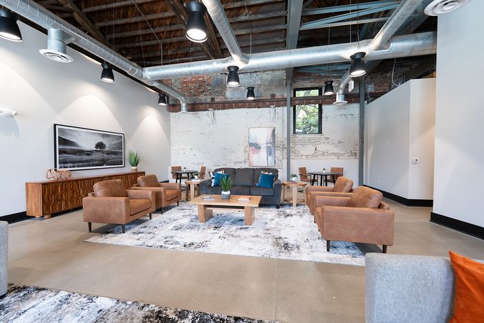 Trendy loft-style lounge with stylish leather seating, rustic brick walls, and industrial ceiling accents, offering a cozy and modern ambiance.