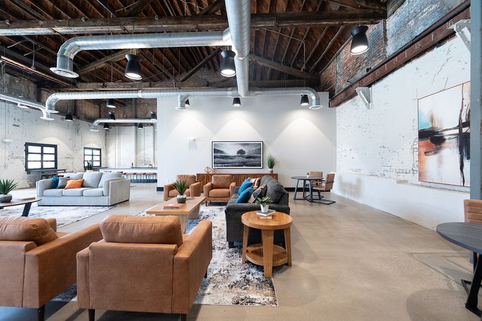 Loft-style clubhouse and lounge with chic industrial elements, featuring exposed brick walls, ductwork, and modern furnishings.