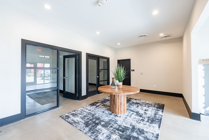 Modern lobby with sleek glass doors, a chic wooden table, and contemporary decor, offering a welcoming atmosphere.