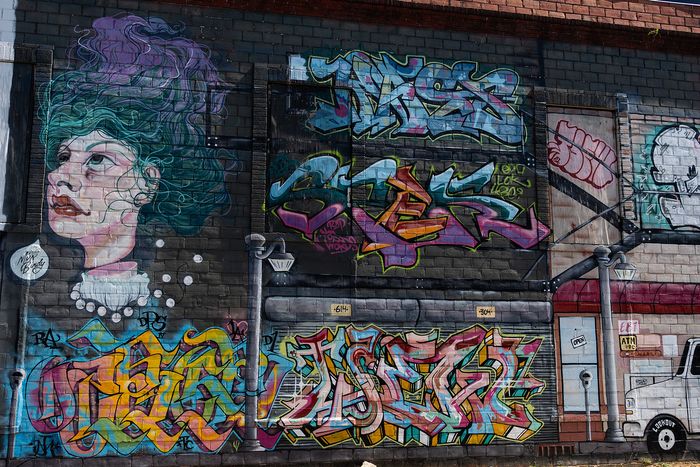 Vibrant urban mural featuring an artistic blend of colorful graffiti and a striking portrait on a city wall.