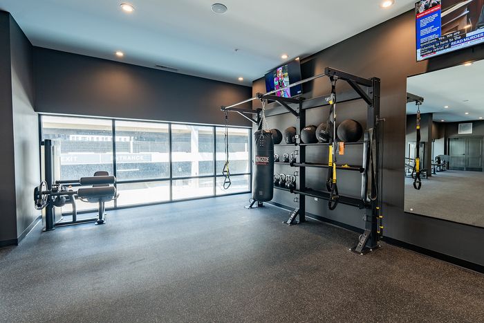 Modern fitness room with large windows, gym equipment, and a sleek black interior design.
