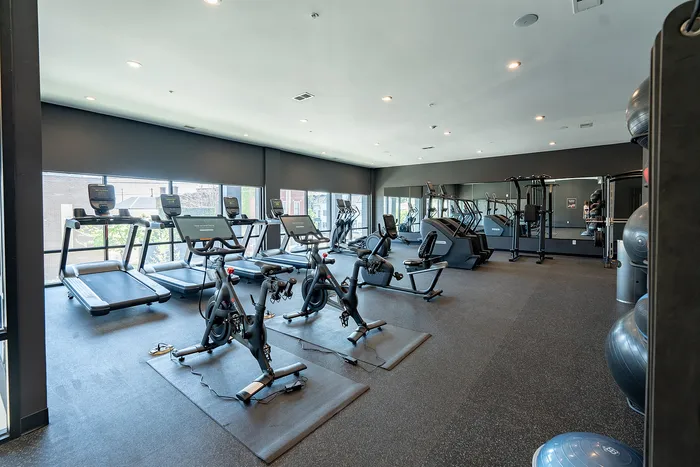 Modern fitness center featuring state-of-the-art exercise equipment, including treadmills and stationary bikes, in a spacious and well-lit environment.