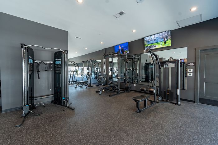 Modern, well-equipped gym with sleek fitness machines and large mirrors in a bright, spacious setting.