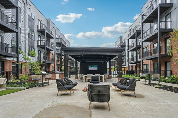 Modern apartment complex courtyard featuring stylish outdoor seating, lush greenery, and vibrant communal spaces.