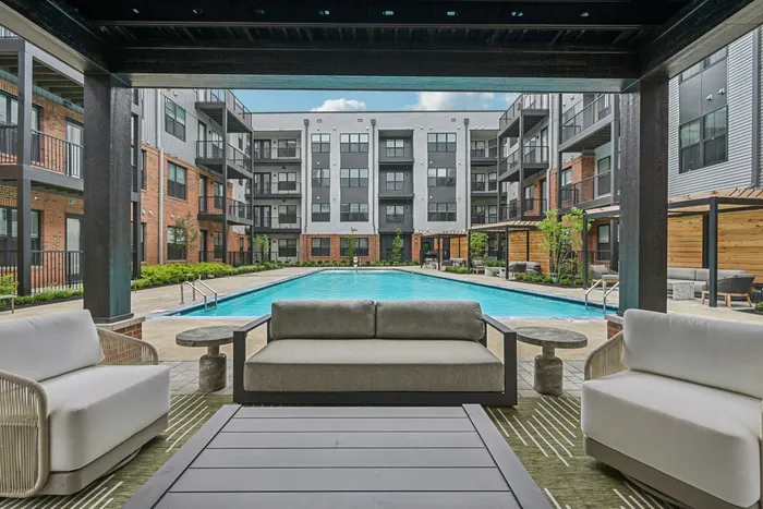 Elegant apartment complex featuring a luxurious pool and modern outdoor seating, perfect for relaxation and leisure.