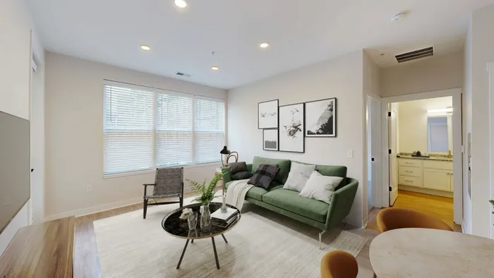 Inviting living room with a modern green sofa, elegant decor, and abundant natural light through large windows.