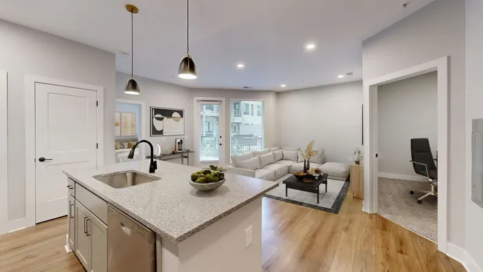 Modern open-concept living space featuring a sleek kitchen island, cozy living room with a sectional sofa, and a versatile office nook.