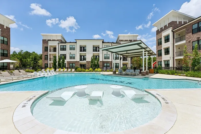 Round area of a pool with three in-water lounge chairs and two tables
