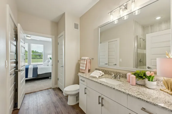 Bathroom vanity with granite countertops, white cabinets, and pink candles and towels