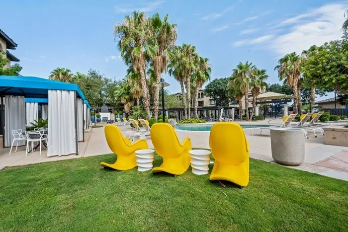 Outdoor seating and landscaping near pool and shaded tables Lunaire Apartments | Goodyear, Arizona
