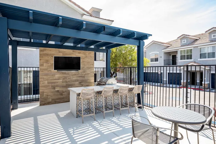 Stylish outdoor patio with a modern pergola, bar seating, and an integrated television.