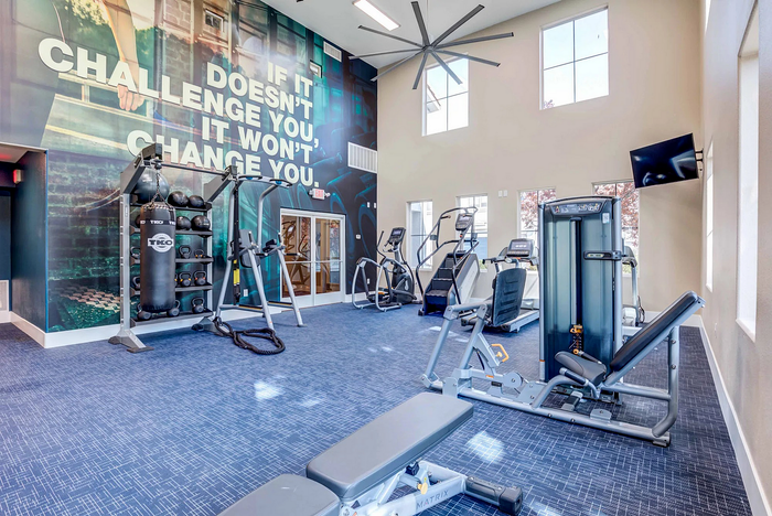 Bright and modern fitness center with exercise equipment and motivational wall art.