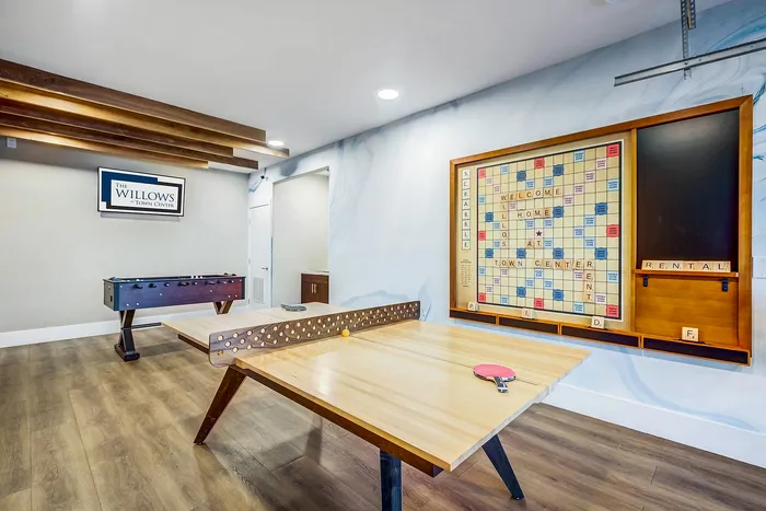 Inviting game room with a ping pong table and foosball, featuring a giant Scrabble board on the wall at The Willows.