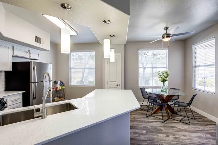 Modern kitchen with sleek countertops and adjacent dining area featuring a glass table and stylish chairs.