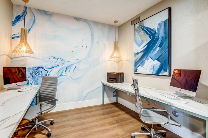 Modern home office with sleek desks, abstract wall art, and chic lighting fixtures.