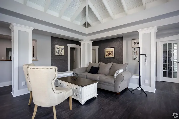 Elegant living room with vaulted ceiling, featuring a plush gray sofa, stylish armchairs, and modern decor.