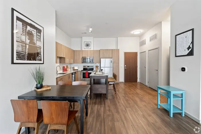 Modern open-plan kitchen and dining area with sleek wooden flooring, stylish furnishings, and stainless steel appliances.