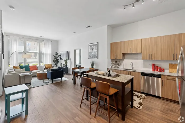 Modern open-concept apartment featuring a bright living area with colorful accents, stylish kitchen with wood cabinets, and inviting dining space.