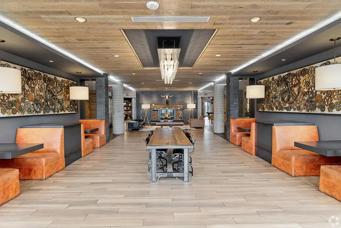 Luxurious apartment lobby with chic industrial design, featuring cozy leather seating, a modern fireplace, and a grand chandelier.
