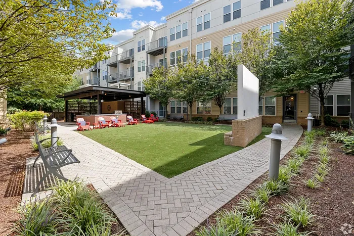 Inviting outdoor courtyard with lush greenery, comfortable seating, and modern apartment building backdrop, ideal for relaxation and social gatherings.
