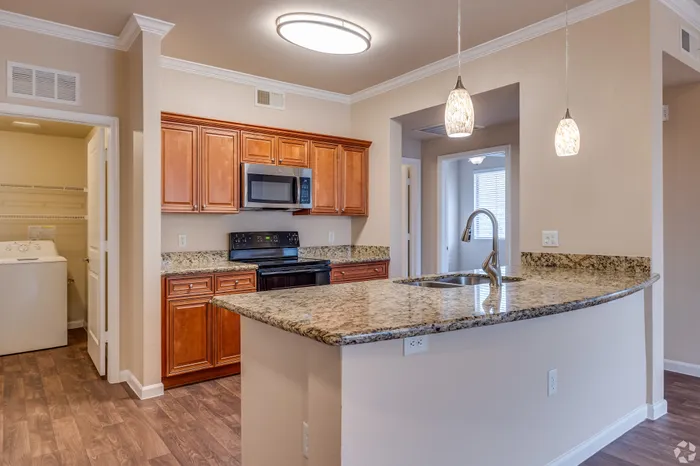 Modern kitchen with elegant granite countertops, cherry wood cabinets, and sleek stainless steel appliances, enhanced by stylish pendant lighting.