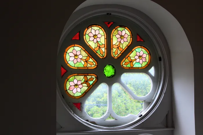 Elegant round stained glass window featuring vibrant floral designs, adding historic charm and colorful illumination to any space.