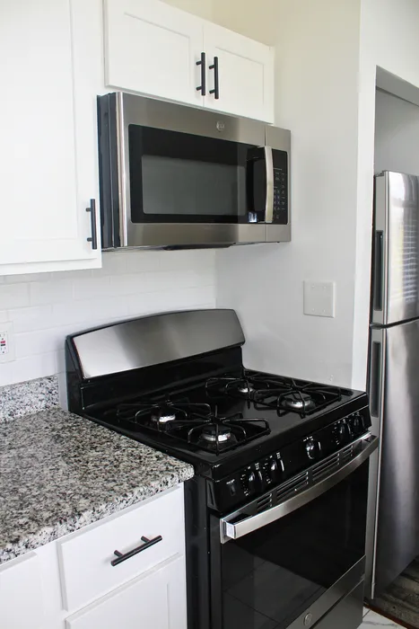 Modern kitchen with sleek stainless steel appliances, granite countertops, and stylish white cabinetry.
