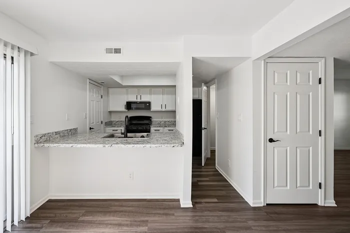 Modern kitchen with sleek granite countertops, white cabinetry, and open layout in a stylish apartment.