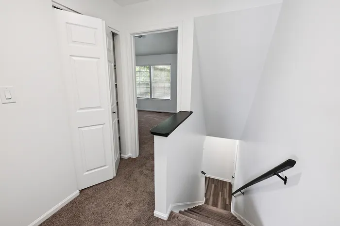 Inviting staircase leading to a bright room with large windows and plush carpeting, perfect for a cozy living space.