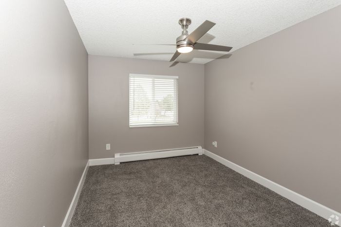 Bright unfurnished room with plush carpet and modern ceiling fan, offering a peaceful retreat with natural light.