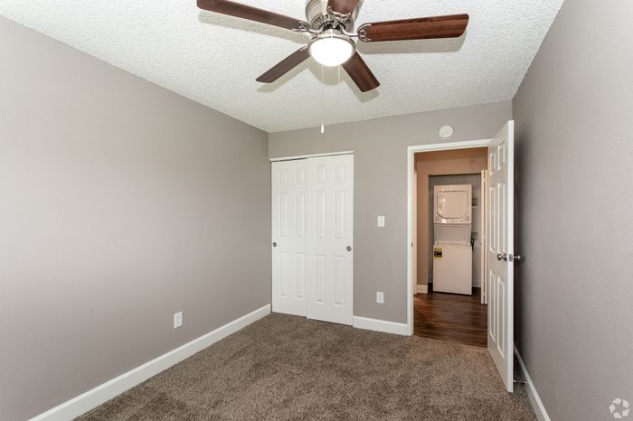 Bright and cozy bedroom featuring plush carpet, ceiling fan, and convenient in-unit laundry access.
