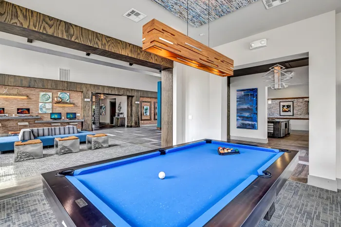 Chic community lounge with a vibrant blue pool table, modern artwork, and elegant furnishings creating a stylish recreational space.