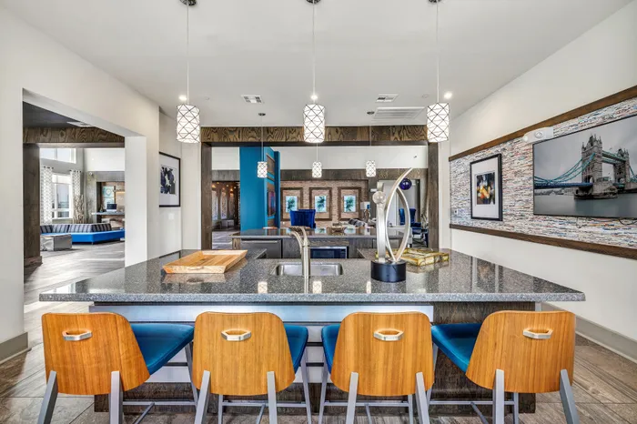 Elegant open-concept kitchen and living area with modern decor, featuring a stylish island, wooden stools, and artistic lighting.