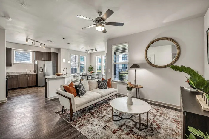 Elegant open-concept living room with modern kitchen, featuring sleek appliances, a spacious sofa, and stylish decor, bathed in natural light.