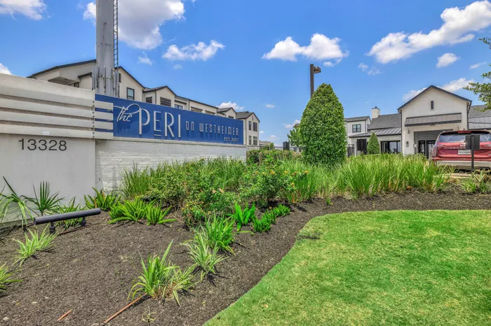 Inviting entrance to The Peri on Westheimer, showcasing lush landscaping and modern architecture under a bright blue sky.