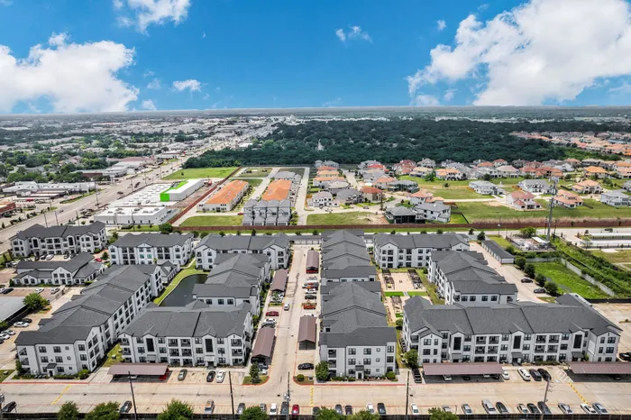 Vibrant aerial view of a modern apartment complex surrounded by lush greenery and a thriving neighborhood, offering convenient urban living.