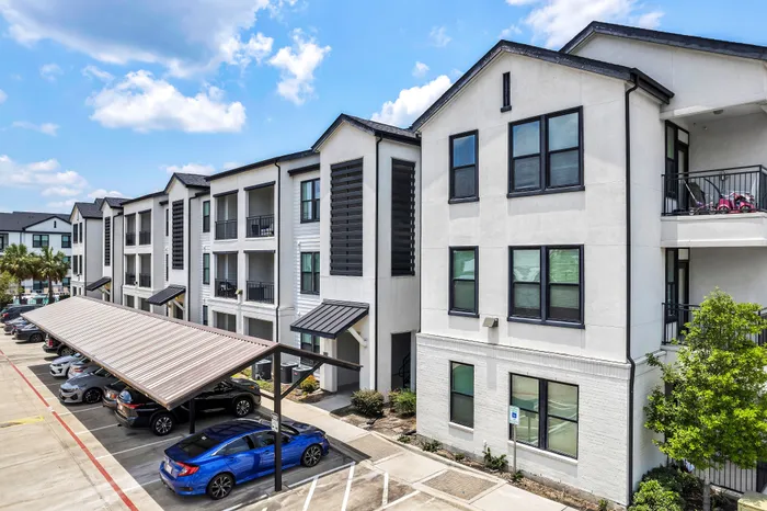 Modern apartment complex with stylish balconies and ample parking under a clear blue sky.