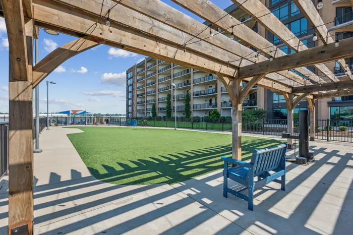 Scenic apartment courtyard featuring a wooden pergola and green lawn, perfect for relaxation and outdoor activities.