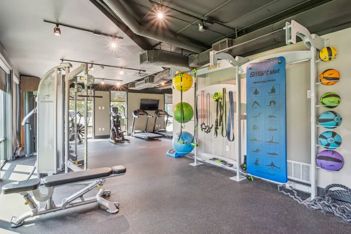 Modern fitness center featuring state-of-the-art equipment, vibrant exercise balls, and an inspiring stretching area.