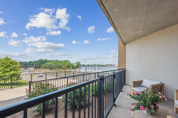 Charming balcony view overlooking a serene marina with lush greenery and vibrant flowers, perfect for relaxation and enjoying nature.