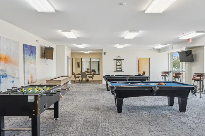 Vibrant game room with sleek pool tables, foosball, and stylish seating, perfect for social gatherings.