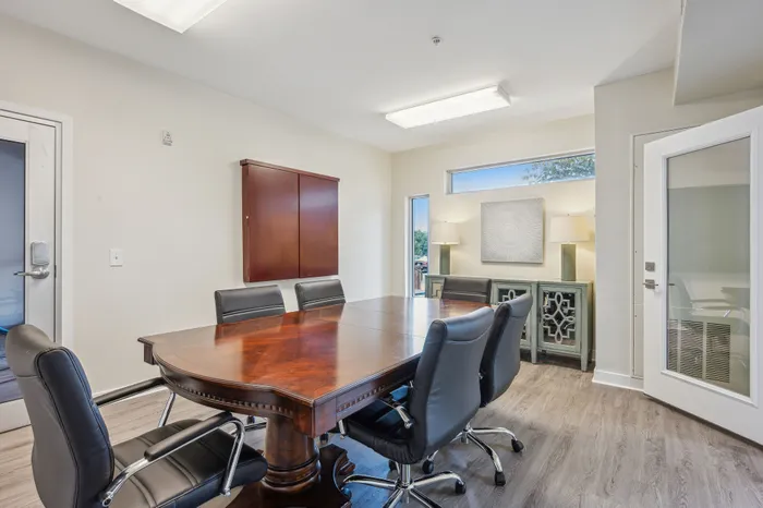Elegant conference room featuring a polished wooden table, comfortable leather chairs, and bright natural lighting for an inspiring workspace.